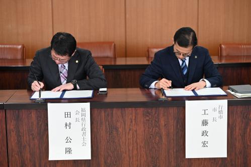 協定書に署名する田村会長と工藤市長